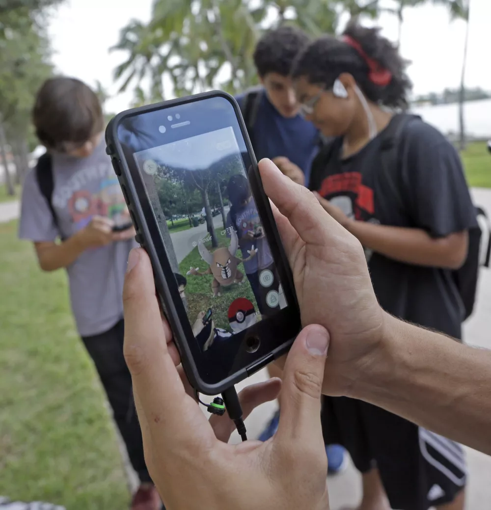 FILE - In this Tuesday, July 12, 2016, file photo, Pinsir, a Pokemon, is found by a group of Pokemon Go players at Bayfront Park in downtown Miami as the "Pokemon Go" craze has sent legions of players hiking around cities and battling with "pocket monsters" on their smartphones. Nintendo suffered as a latecomer to smartphone games but is seeing the deep wealth of its franchise characters pay off with the success of &acirc;&euro;śPokemon Go,&acirc;&euro;ť even without a launch yet in Japan. The Japanese game maker was starting to look like a casualty of history until the game was launched in the U.S. earlier this month. Not anymore. (AP Photo/Alan Diaz, File)
