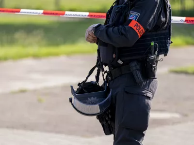 27 June 2024, Thuringia, Erfurt: A police officer stands in front of a police cordon near the suspected crime scene in Erfurt, where a man was shot dead. A large-scale police operation is currently underway. Photo: Jacob Schr&ouml;ter/dpa