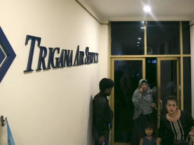 People walk into the entrance of Trigana Air's office in Jakarta, Indonesia August 16, 2015. Villagers in Indonesia's remote and mountainous eastern Papua region reported that an aircraft had crashed, a Trigana Air official said on Sunday, several hours after an aircraft carrying 54 people went missing, media reports said. REUTERS/Darren Whiteside